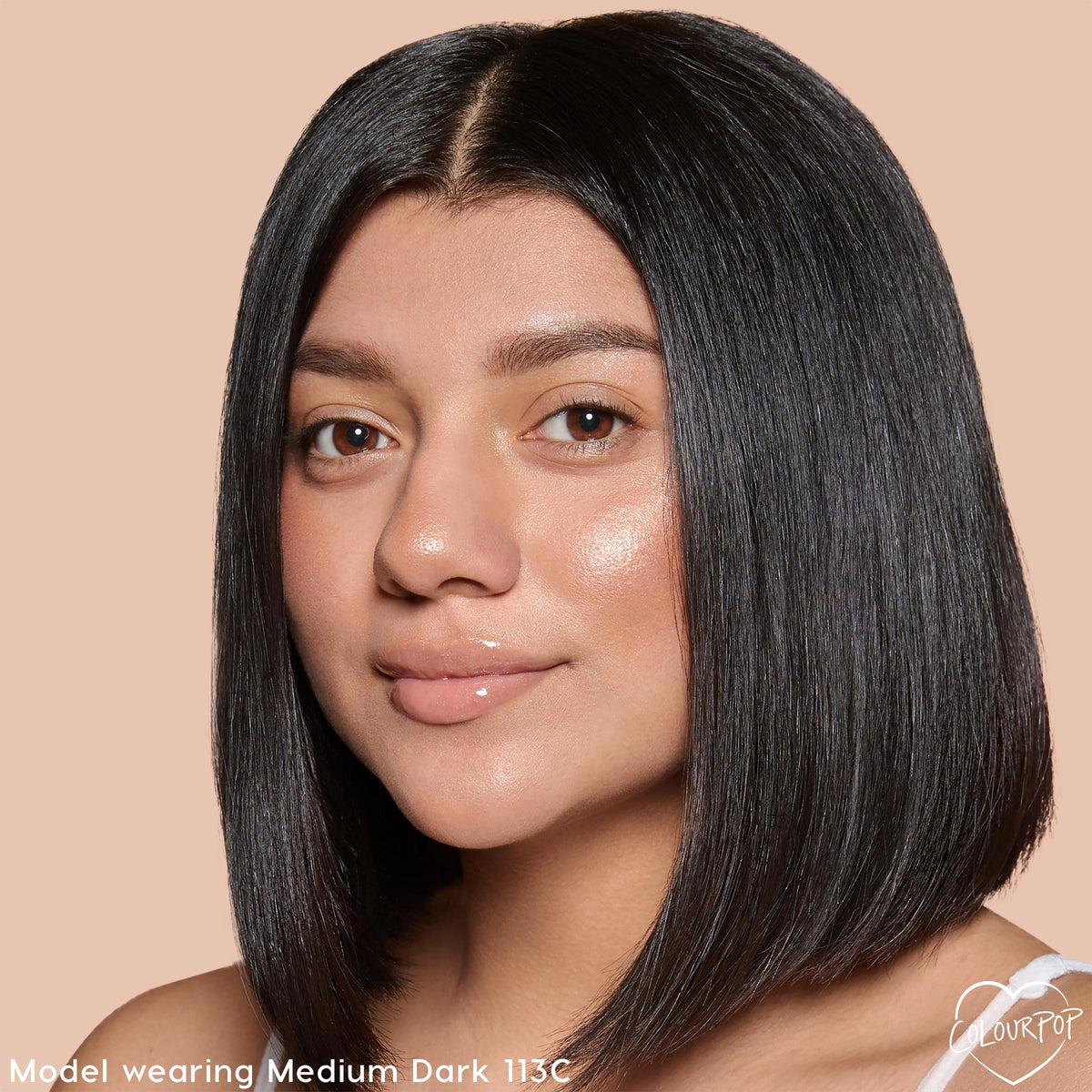 ColourPop Pretty Fresh Creamy Concealer in Medium Dark 113 C worn by a model, showing natural dewy coverage and brightened under-eyes; close-up portrait on a beige background for accurate shade reference.