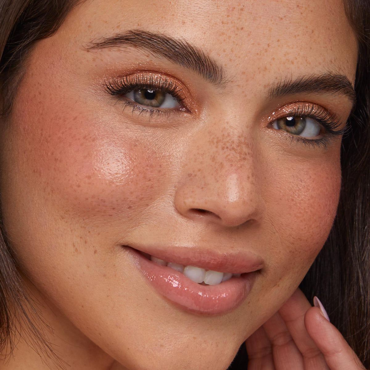 Shimmery lids showcase ColourPop Super Shock Shadow Ritz, a sparkly champagne wash catching light on the upper lids; close-up of a smiling model with freckles, peachy blush, and glossy nude lips for soft everyday glam.