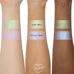 ColourPop Shadow Stix Cute and Feisty swatched on three arms - two bands per arm labeled Alien Vibes (gold‑green shimmer) and He’s All Yours (pink‑lilac blue shift) - showing creamy payoff across light, medium, and deep skin tones.