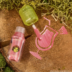 ColourPop Ultra Glossy Lip in Ogress, open with a green-capped doe-foot swiping shimmery pink gloss into a cocktail glass shape on a mossy wood stump, clear bottle showing Shrek’s Fiona artwork and a high-shine, glittery finish.