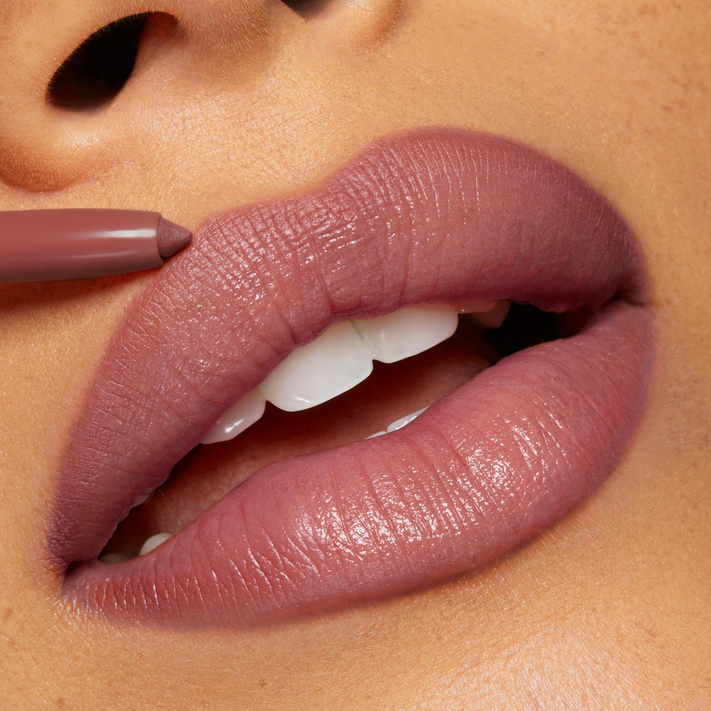 ColourPop Group Chat So Juicy Plumping Lip Liner with Peptides lining full lips in a mauve‑nude shade, pencil tip defining the cupid’s bow for a smooth, glossy, fuller look in a tight close-up.