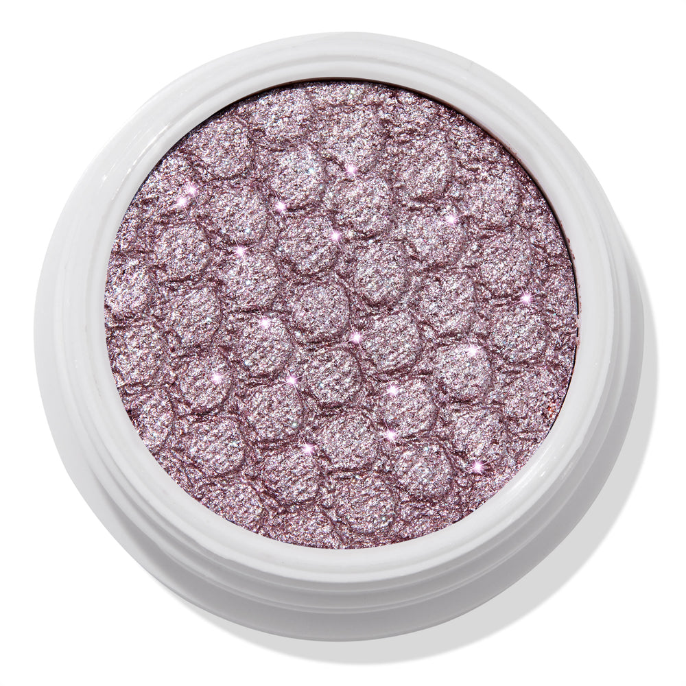 ColourPop The Griffith Super Shock Shadow eyeshadow showing a metallic cool-toned lavender-pink shimmer, pressed with a quilted honeycomb texture in a white round pot, reflecting silver sparkles for high-shine lids.