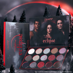 ColourPop Twilight Forever palette trio from the Twilight collection, opened to show 15 shimmer and matte eclipse-inspired eyeshadow pans in reds, silvers, and neutrals, set against a dark forest and blood-red moon backdrop for dramatic makeup looks.