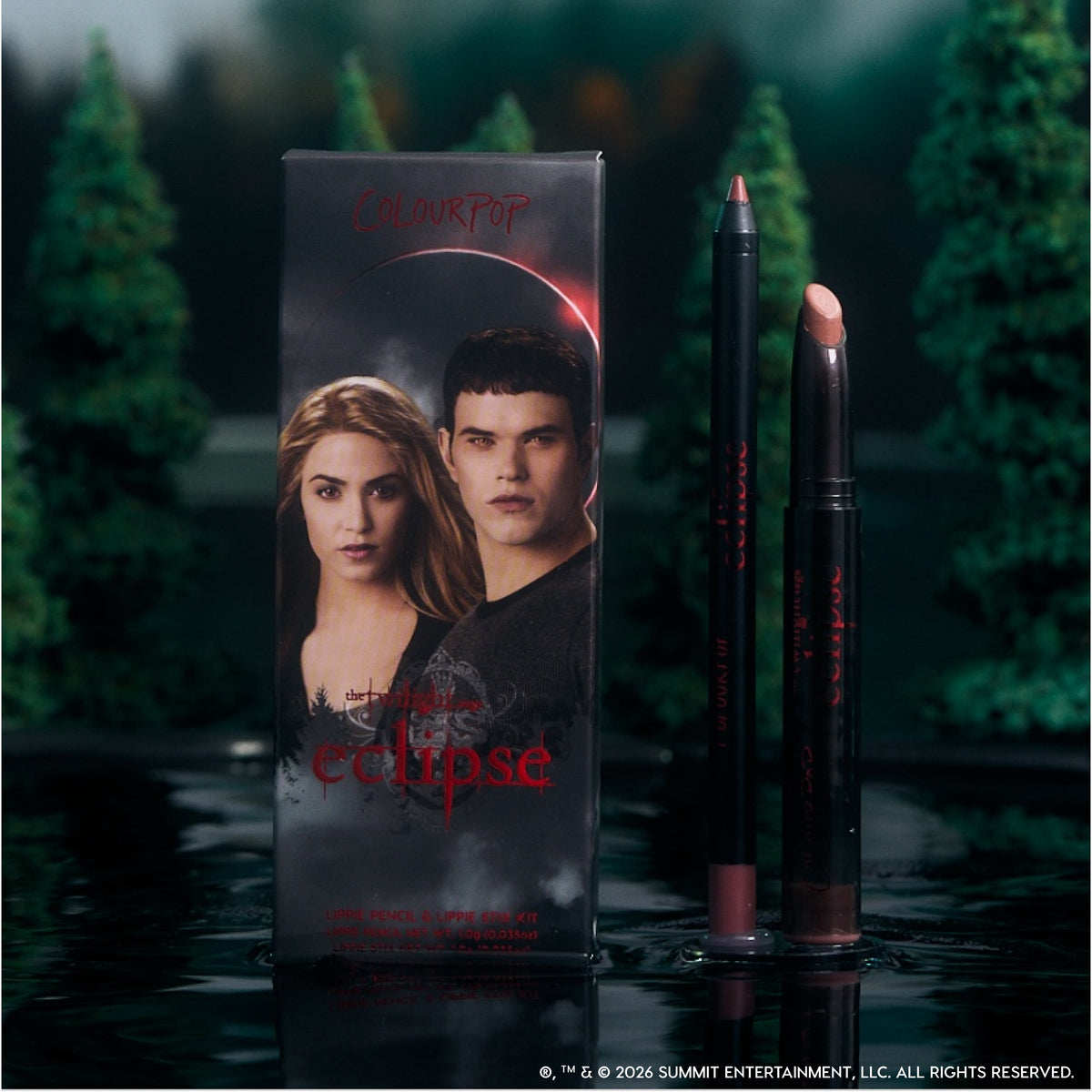 ColourPop Opposites Attract Lippie Stix and lip pencil from the Twilight Eclipse collection stand beside their character-adorned box on a reflective lake surface, surrounded by dark evergreen trees for a moody, cinematic makeup display.