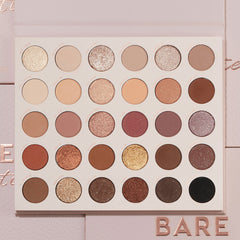 Bare Necessities ColourPop Shadow Palette showcasing 30 neutral matte and shimmer shades in a 6x5 grid - ivory, taupe, mauve, bronze, gold, deep brown, and black - laying open on blush-pink packaging with BARE lettering, ideal for everyday looks.