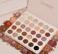 ColourPop Shadow Palette Bare Necessities lies open, showing 30 pressed neutral shades - matte and shimmer - ranging from ivory, taupe, and peach to bronze, plum, and black, arranged in rows amid scattered crushed pigments on a textured surface.