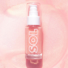 ColourPop SOL Shimmering Dry Oil in Pink Champagne stands upright with a pump and clear cap, showcasing rose-pink, gold-flecked oil in a glass bottle labeled SOL against a luminous pink glitter background.