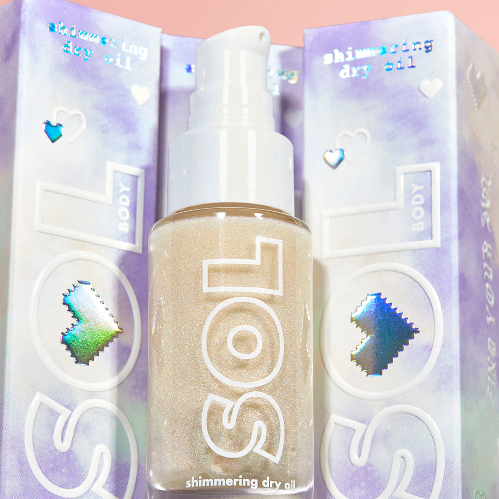 Rainbow Glow SOL Shimmering Dry Oil bottle pumps out golden, sparkly body oil, set against iridescent lavender packaging with holographic hearts; ColourPop SOL Shimmering Dry Oil for a radiant, sunlit glow.