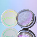 ColourPop Jelly Much Shadow Hallucinogenius opens to reveal an iridescent lavender-blue jelly eyeshadow with metallic shimmer, its white lid with COLOURPOP logo beside it, mirrored on a glossy surface against a pastel blue-purple backdrop.